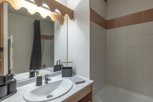 a bathroom with a sink and a tub and a mirror at Appartement à Samoëns – 6 couchages in Samoëns