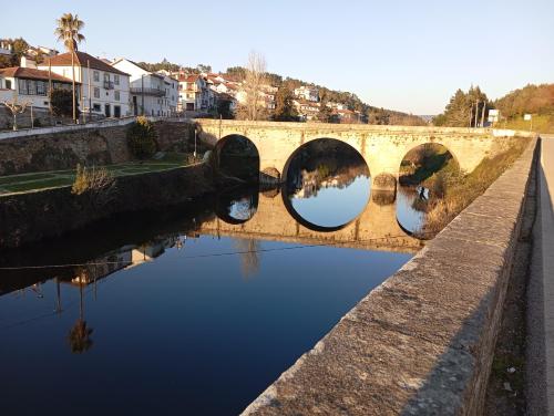 a bridge over a river with a reflection in the water at A Encantada in Alqueve