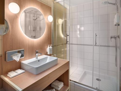 a bathroom with a sink and a shower at Kyriad Prestige Hotel Clermont-Ferrand in Clermont-Ferrand