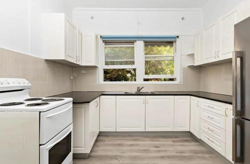 eine Küche mit weißen Schränken und weißen Geräten in der Unterkunft Central Burwood Shared Stay in Sydney
