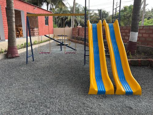 a playground with a yellow and blue slide at Krushnam Villa Resort Somnath by The Cellton Hotels & Resorts in Somnath