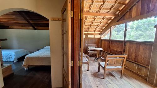 a bedroom with a bed and a table and chairs at Chalé Vista Pedra Partida in Monte Verde
