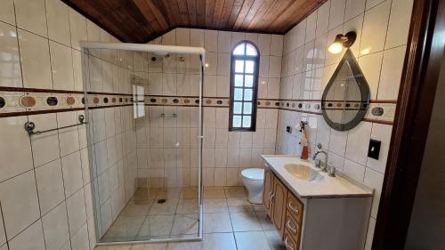 a bathroom with a shower and a sink and a toilet at Chalé Vista Pedra Partida in Monte Verde