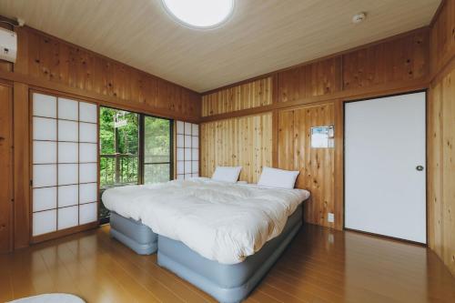 a bedroom with a bed in a room with wooden walls at ItsumoYuki in Atami