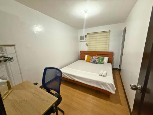 a small bedroom with a bed and a table at 2-Bedroom Condo in Imus Cavite with UNLI WIFI, 50" TV, Netflix, Family Computer, Pool in Imus