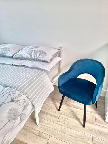 a bedroom with a blue chair next to a bed at Studio flat close to Heathrew Airport in Northolt