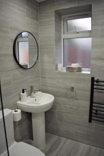 a bathroom with a sink and a mirror and a toilet at Studio flat close to Heathrew Airport in Northolt