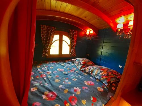 łóżko w małym pokoju z oknem w obiekcie Roulotte appartement Cosy w mieście Brennes
