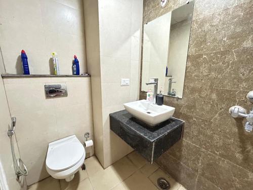a bathroom with a sink and a toilet and a mirror at Elite BnB, High Rise with city view in Ghaziabad