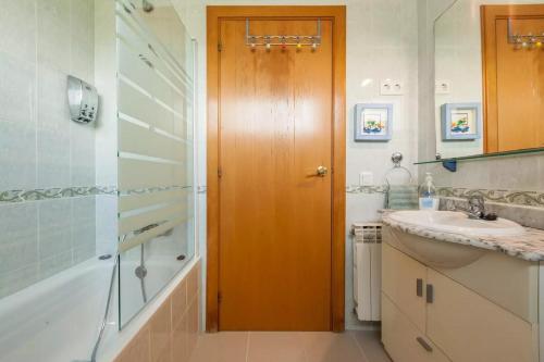 a bathroom with a wooden door and a sink and a shower at La Cantonada in Sant Pere de Ribes