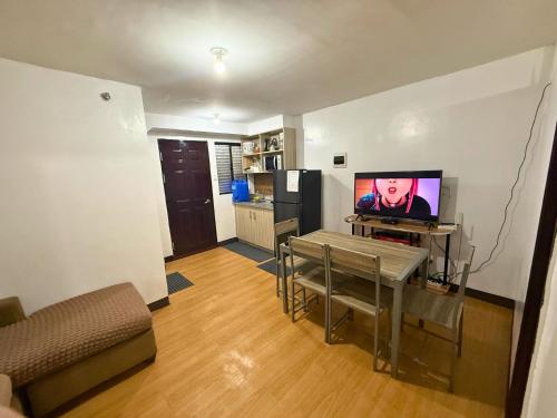 a living room with a table and a television in it at 2-Bedroom Condo in Imus Cavite with UNLI WIFI, 50" TV, Netflix, Family Computer, Pool in Imus