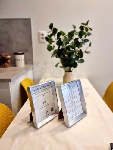two signs on a table with a vase of plants at Apartment Banska - City Centre & Private Parking in Banská Bystrica