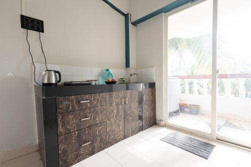 アーポラにあるSpacious 1BHK WiFi Balcony and Pool View near Anjunaのカウンターと大きな窓のあるキッチン