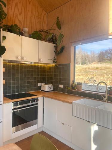 a kitchen with white cabinets and a sink and a window at Mountain View Barn with Spa in Queenstown