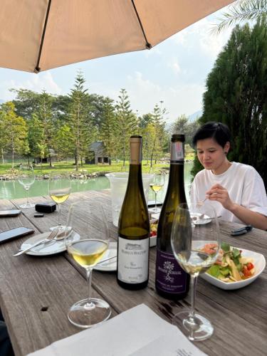 una donna seduta a un tavolo con due bottiglie di vino di Villa At On Organic Farm a Ban Wak
