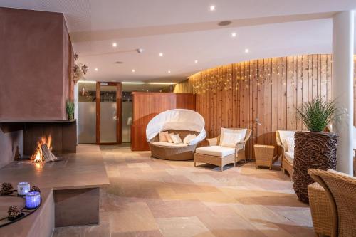 a lobby with a fireplace and a couch and chairs at Relax & Vitalhotel Adler in Schruns-Tschagguns