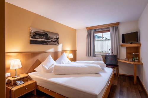 a hotel room with two beds and a television at Relax & Vitalhotel Adler in Schruns-Tschagguns