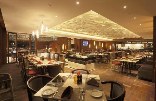 a dining room with tables and chairs in a restaurant at Hotel East End Delhi Aiport in New Delhi