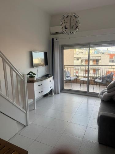 a living room with a couch and a television and a balcony at Super Monaco 2 in Beausoleil