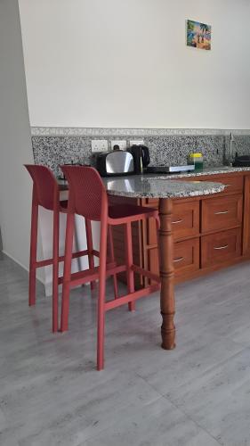 a table with two red chairs and a counter at Trwa Koko Self-catering in Grand'Anse Praslin