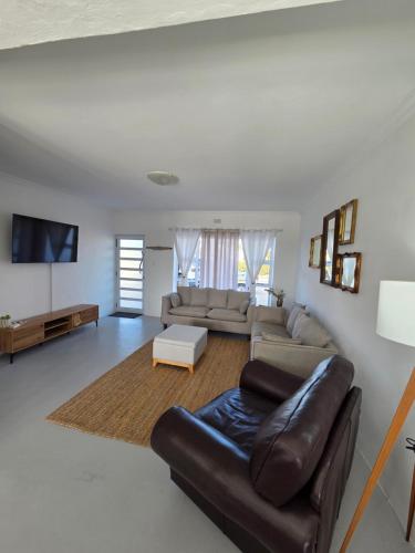 a living room with a leather couch and a tv at Stoepstories in Yzerfontein