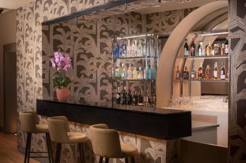 a bar with chairs and bottles on a wall at NH Collection Palermo Palazzo Sitano in Palermo
