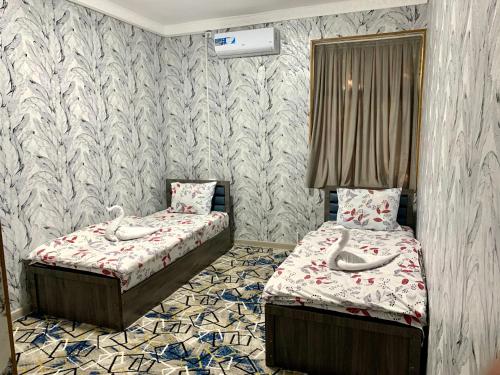 two twin beds in a room with wallpaper at AsiaHotel in Kokand