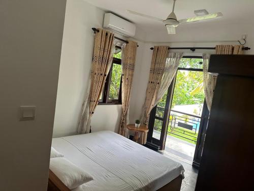 a bedroom with a bed and a large window at Lanka Villa Beruwala in Beruwala