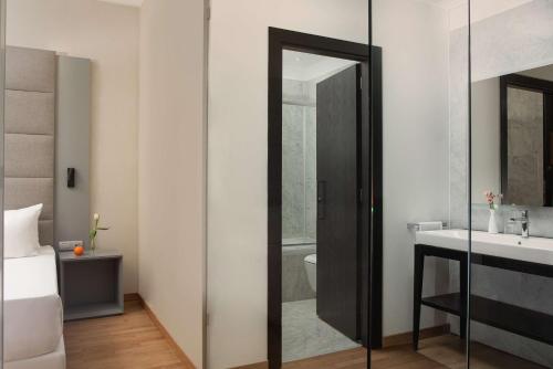 a bathroom with a glass shower door next to a sink at NH Collection Palermo Palazzo Sitano in Palermo