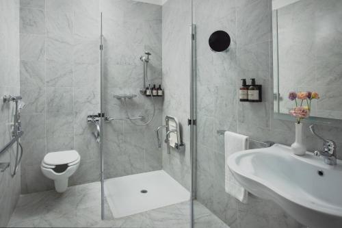 a bathroom with a shower and a toilet and a sink at NH Collection Palermo Palazzo Sitano in Palermo