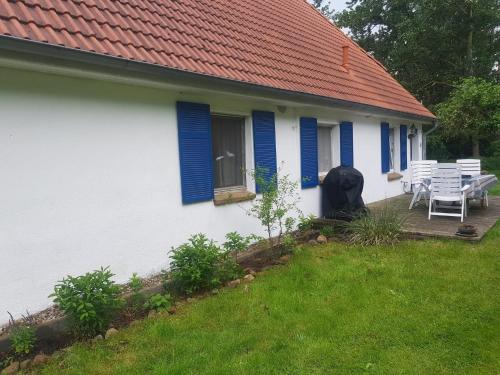 a white house with blue shutters and a table and chairs at Haus Gorch Fock in Tremt