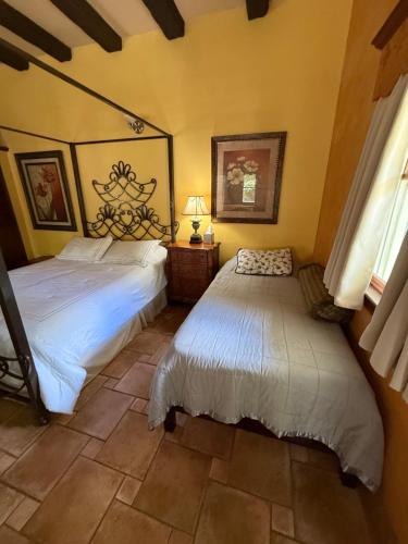 two beds in a bedroom with yellow walls at Flowertown Bed and Breakfast in Summerville