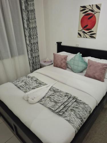 a bed with white sheets and pillows on it at Saffron Homes A6 in Eldoret