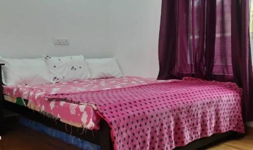 a bedroom with a bed with a pink blanket on it at Golden Villa in Vagamon