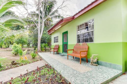 a green house with two chairs on the porch at La Casita at Midas Belize in Trapiche