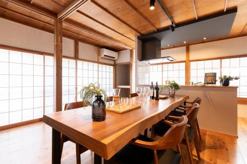 a dining room with a large wooden table and chairs at 一棟貸し 小海の宿 いおり in Numazu