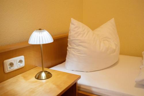 a bed with a pillow and a lamp on a table at Hotel-Gasthof Sondergeld in Hofbieber