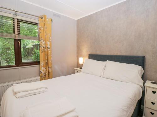 a bedroom with a white bed and a window at Costapacket in Troutbeck Bridge