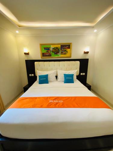 a bedroom with a large white bed with blue pillows at Sangga Buana Resort & Convention Hotel in Pacet