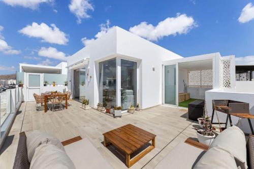 a white house with a patio with a table at CoastLight Rooftop by Bayside Modern Penthouse in Playa Honda