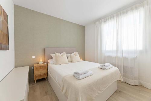a bedroom with a white bed and a window at CoastLight Rooftop by Bayside Modern Penthouse in Playa Honda