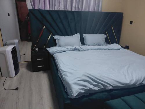a bedroom with a bed with a blue headboard and a television at Mirembe residents in Kampala