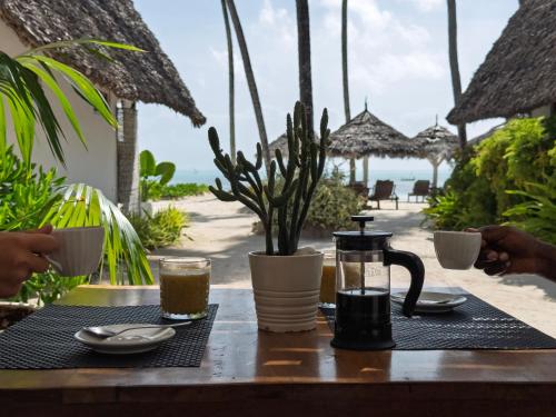 a table with coffee and drinks on the beach at Savera Beach Houses in Jambiani