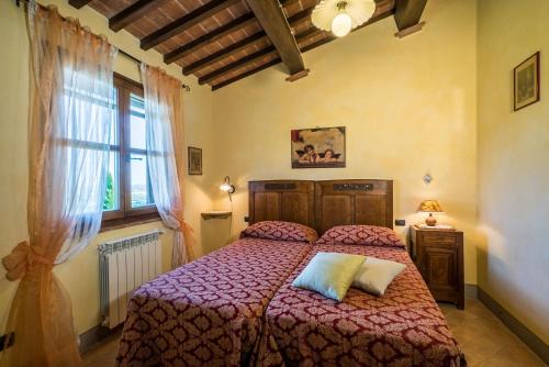 a bedroom with a bed with a red comforter and a window at Villa i Colli in Montaione