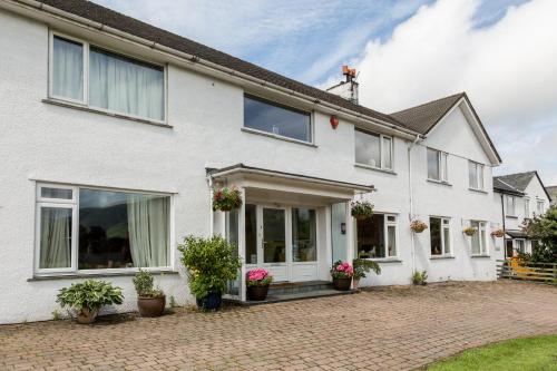 an exterior view of a white house with potted plants at Hermiston Guest House in Keswick