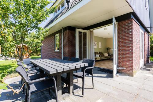 a wooden table and chairs on a patio at Bosvilla Lariks met sauna en hottub | 6 personen - Vakantiepark De Kremmer in Gasselte