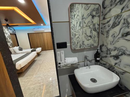 a bathroom with a sink and a bedroom with a bed at Krushnam Villa Resort Somnath by The Cellton Hotels & Resorts in Somnath