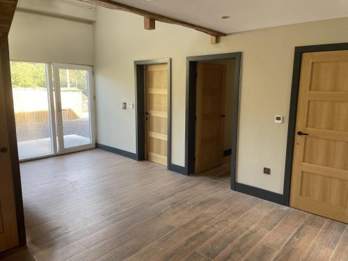 an empty room with two doors and wooden floors at 1 New Dairy Barn in Sunderland Bridge