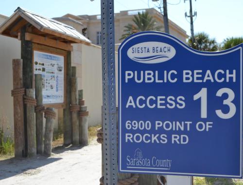 un cartello che recita "accesso alla spiaggia pubblica" di fronte a un edificio di Holiday House 3 a Point O'Rocks