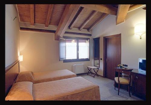 a bedroom with two beds and a television in it at Hotel Fondo Catena in Ferrara